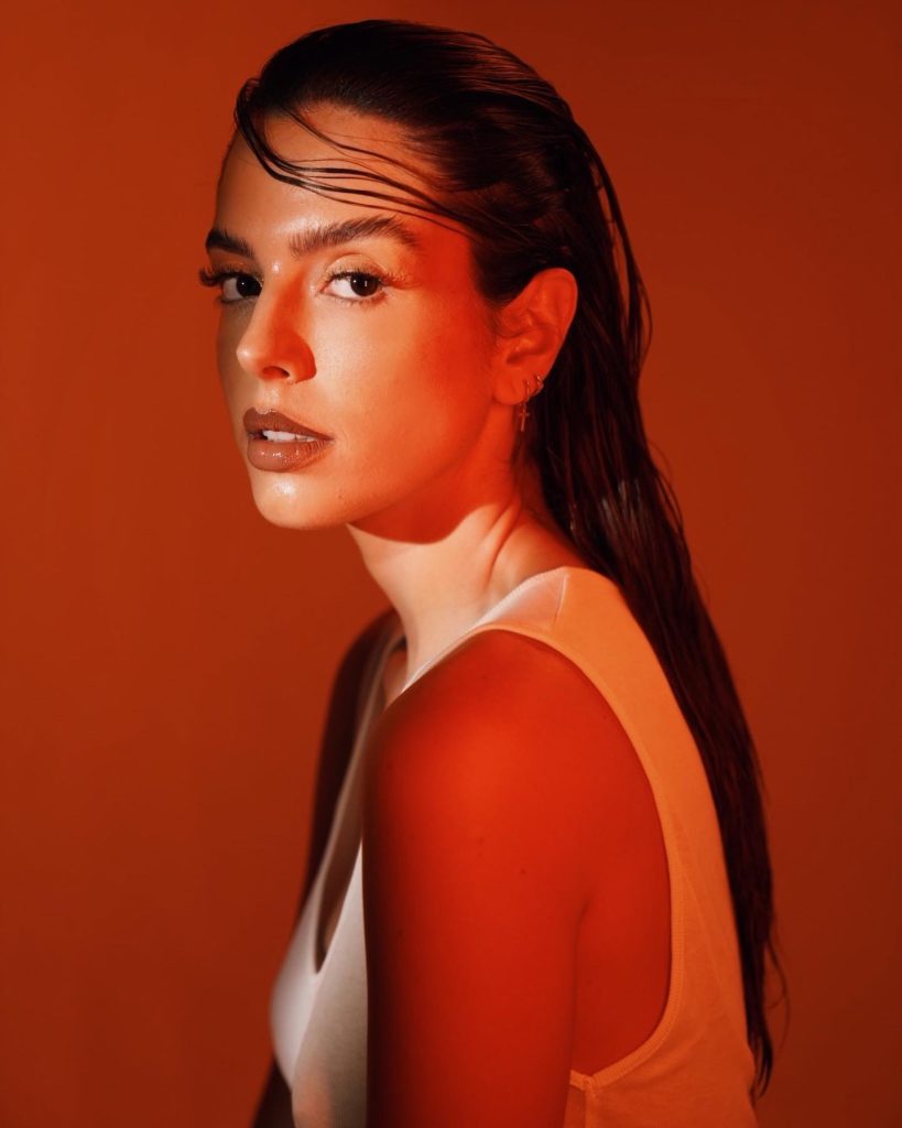 Atriz Giovanna Lancellotti posa sem sutiã com blusinha branca deixando peitinhos à mostra.